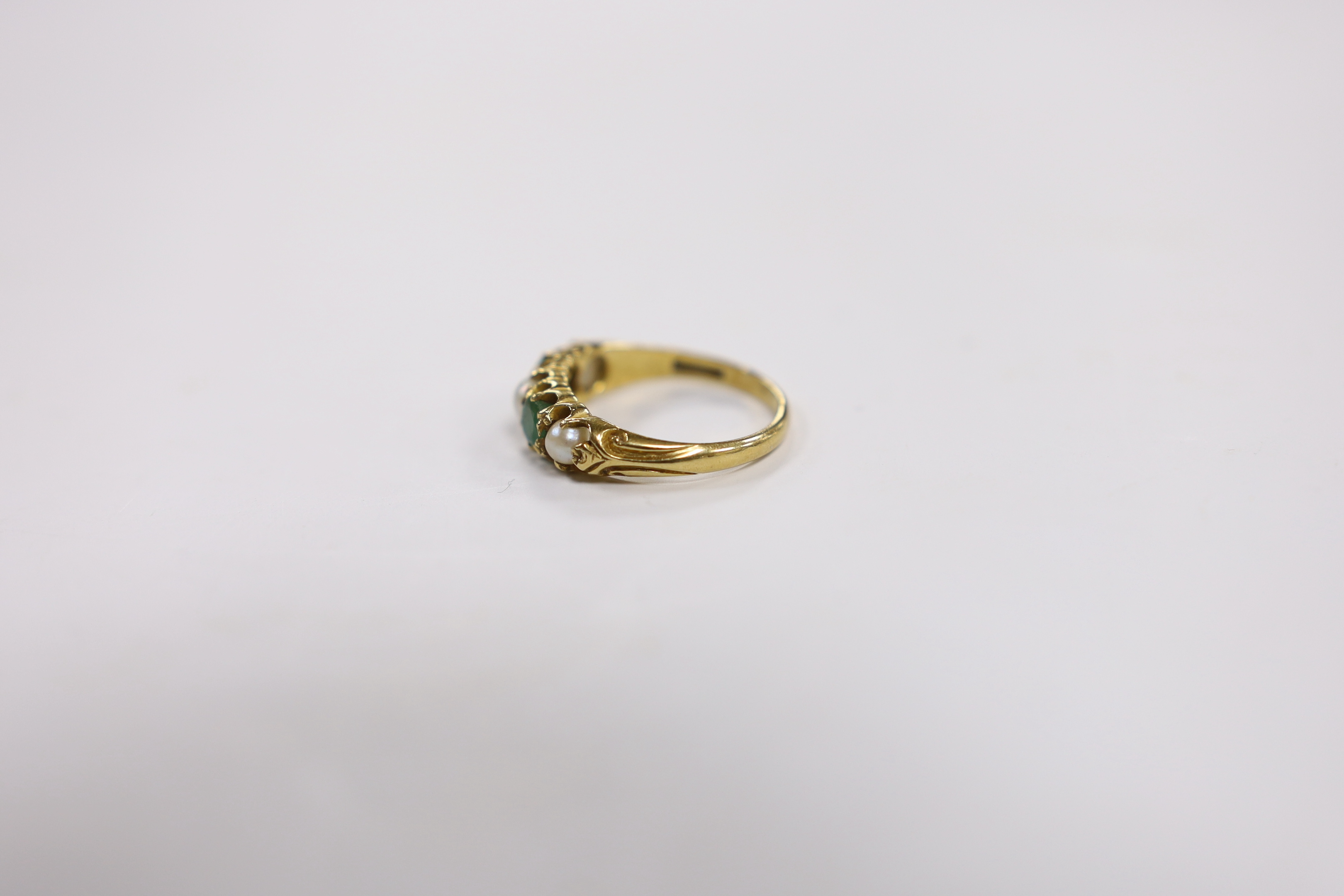 An 18ct, two stone emerald and three stone split pearl set half hoop ring, size P, gross weight 4.1 grams.